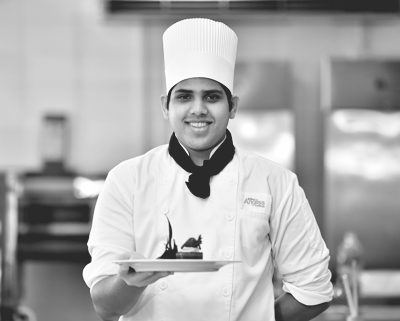 Patisserie chef student holding a desert.